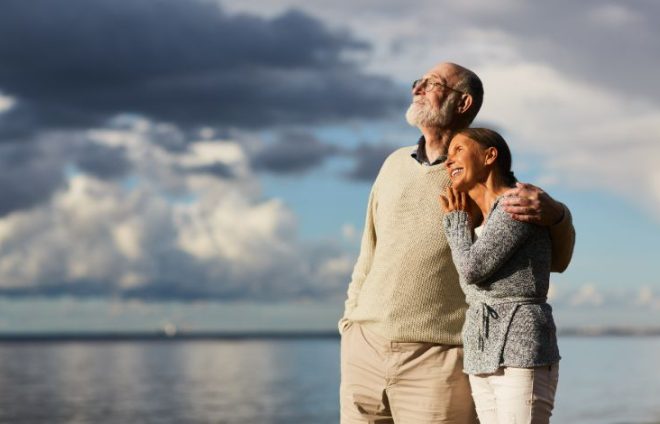 Elderly couple embracing while looking into sunset