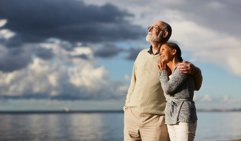 Elderly couple embracing while looking into sunset